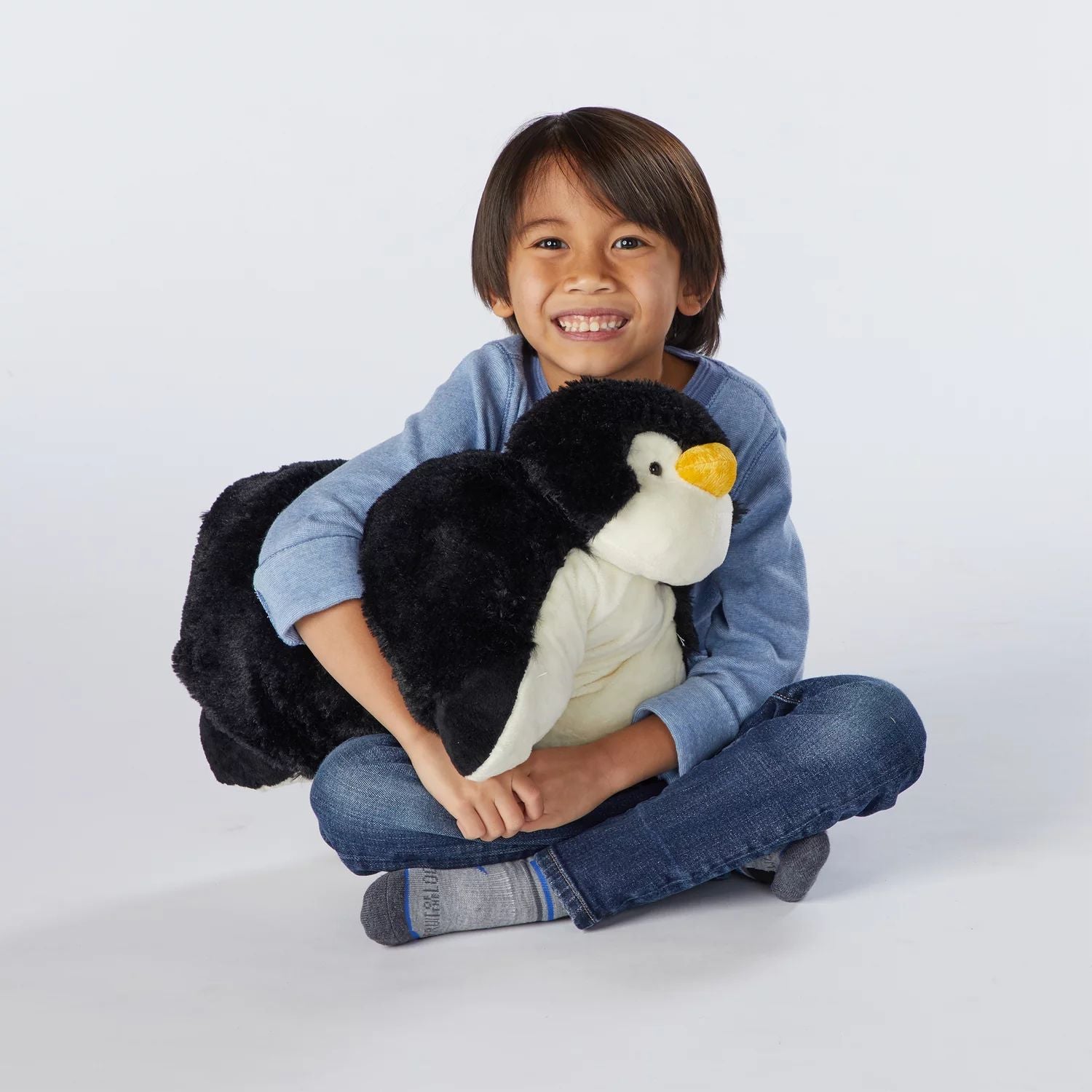 Pet pillow with Pillow Pets signature playful penguin plush toy